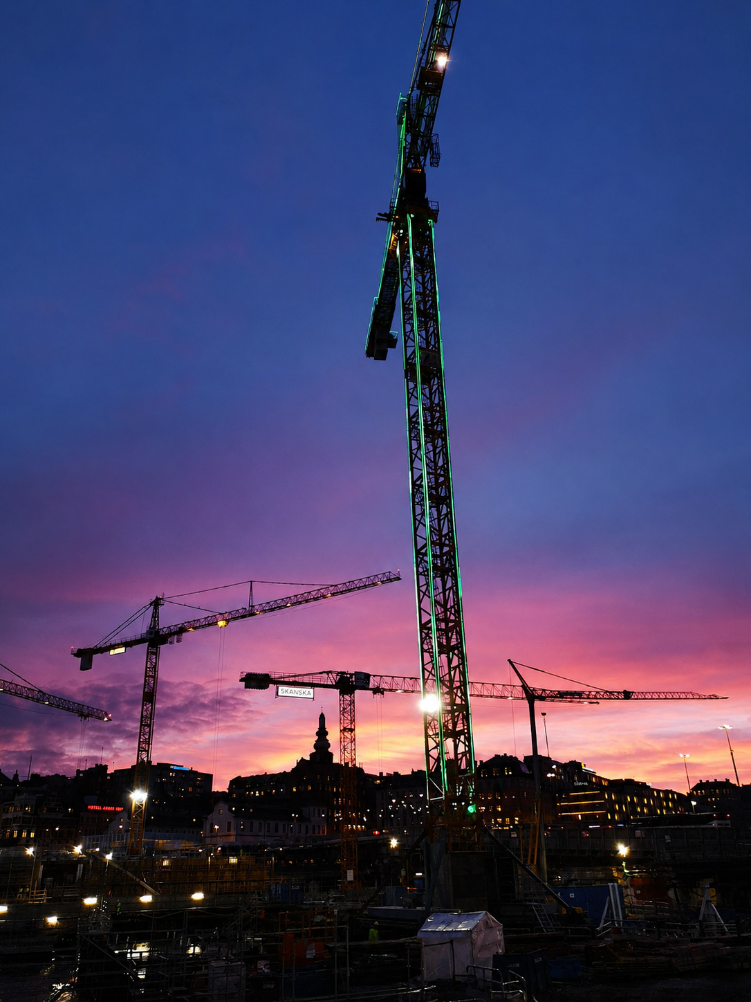 Hög tornkran över Slussen mot en rosa kvällshimmel